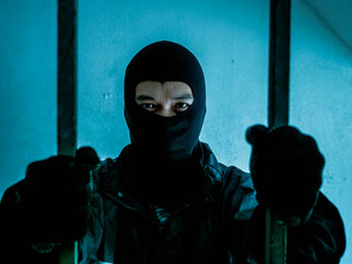 Bandit wearing a mask is An agitated prisoner in jail holding bars, Imprisoned prisoner