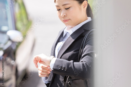 時間を気にするスーツを着た日本人女性 Wall Mural Wallpaper Murals Uts