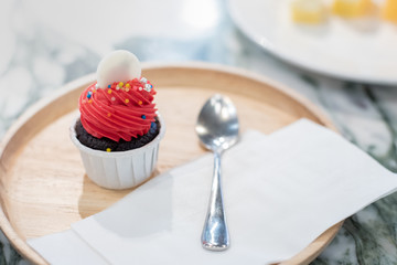 Mini cake red and brown cupcake circle white on top in white cup. wooden plate with spoon and...