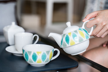 hand holding pot pour tea into a cup.