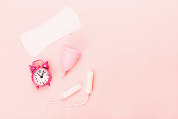 Various sanitary products on pastel pink background.