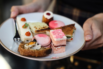 Multiple color sweet  desserts cake and macaroon on dish in woman hand