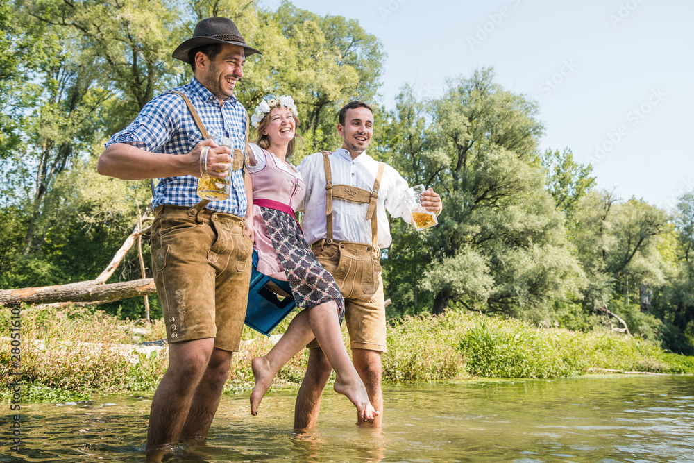 Wall mural Freunde in bayerischen Tracht feiern an der Isar und trinken Bier. Oktoberfest München