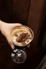 Hand holding glass of fresh cold coffee