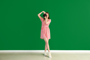 Young female photographer against color wall