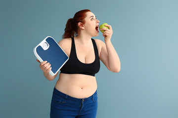 Overweight woman with scales and apple on color background. Weight loss concept