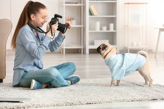 Teenage girl taking photo of her cute dog at home