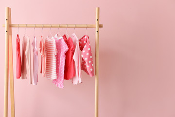 Rack with hanging clothes on color background