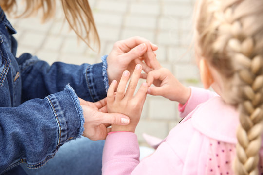 Mother teaching her deaf mute daughter to use sign language outdoors