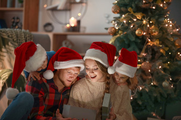Fototapeta na wymiar Happy family opening Christmas gifts in evening