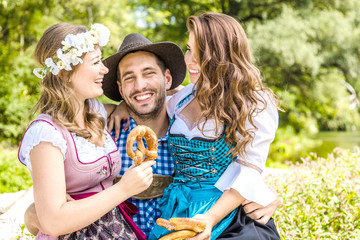 Freunde in bayerischen Tracht feiern an der Isar und trinken Bier. Oktoberfest München