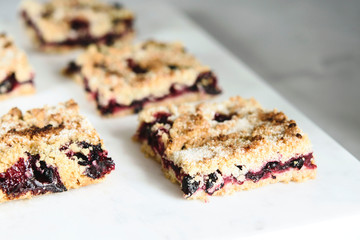 Honeysuckle crumble cake sliced into pieces on grey marble tray. Homemade streusel berries pie.  Selective focus. Haze effect