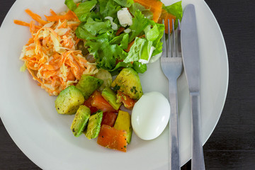 fresh salads on a white plate with stainless steel cuttlery