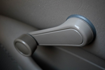Hand crank, non-electric, manual car window in a dove grey color an old vehicle.