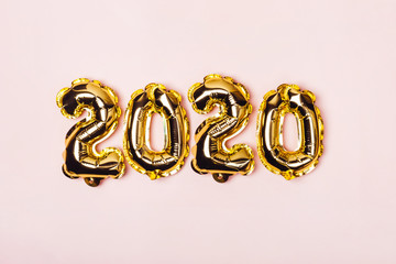 Golden foil balloons on pink pastel background. Inflatable numbers 2020. Christmas concept