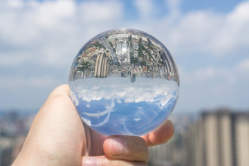 glass ball on a city background with a blue sky and white clouds