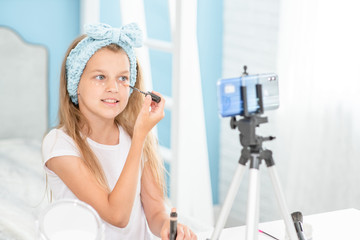 Fototapeta na wymiar Little girl filming the video for her followers about skincare. Kids blogger concept
