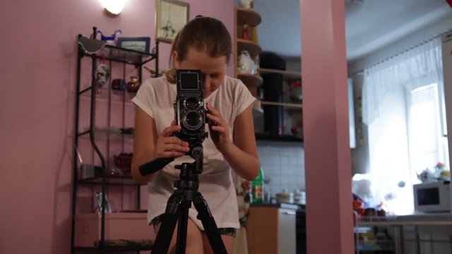 teen girl looks into the mine of a medium format camera aimed at us.