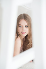 Obraz premium Beautiful young blonde woman with a beautiful body lying on the bed near the window dressed in sexy underwear