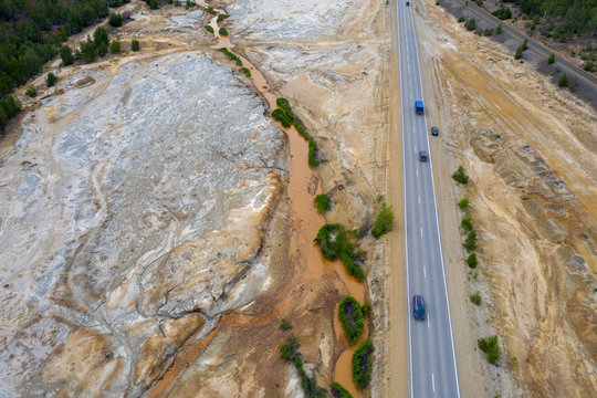 Aerial view; drone flying forward over a polluted river with destroyed ecosystem and copper tailing dump poisoning ground and water; air emissions from industry; environmental disaster in South Ural