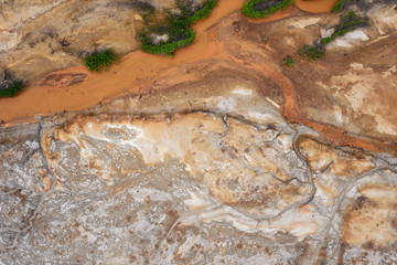 Aerial view; drone flying forward over a polluted river with destroyed ecosystem and copper tailing dump poisoning ground and water; air emissions from industry; environmental disaster in South Ural