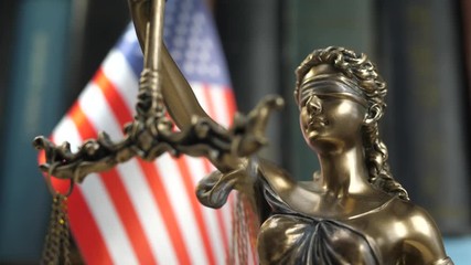 Statue of Lady Justice with Books and United States of America Flag. Tribunal and justice concept. Consultation with insurance lawyer and customer - Powered by Adobe
