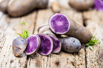 close-up view of fresh raw purple potatoes on wooden table 