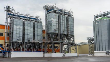 Fototapeta na wymiar Exterior of Agricultural Silo building with storage tanks for agricultural crops processing plant, drying of grains, rape, wheat, corn, soy, sunflower.