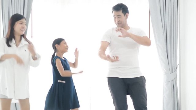 Happy young Asian family dancing together at home.