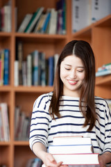 図書室で本を持つ日本人女性