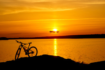 Fototapeta premium silhouette of a bicycle at sunset. drone quadcopter with digital camera flying at sunset