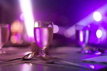 1 glass of water placed on the table In the night restaurant with colorful light.
