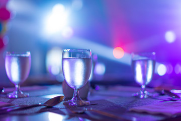 1 glass of water placed on the table In the night restaurant with colorful light.