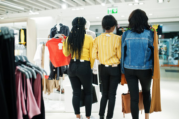 Back of three african woman choosing clothes at store. Shopping day.