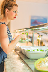 Pretty girl staring straight ahead while having salad in a buffet - Beauty cosmetics