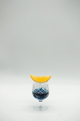 Glass with blue curacao on white background