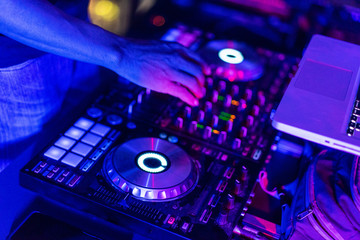 Fototapeta na wymiar A DJ is using music mixer in the nightclub with colorful light