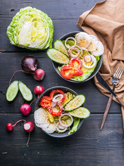 Top view spring salad with radishes, cucumbers, onions, sweet peppers and sesame oil. Vertical shot. Healthy food.
