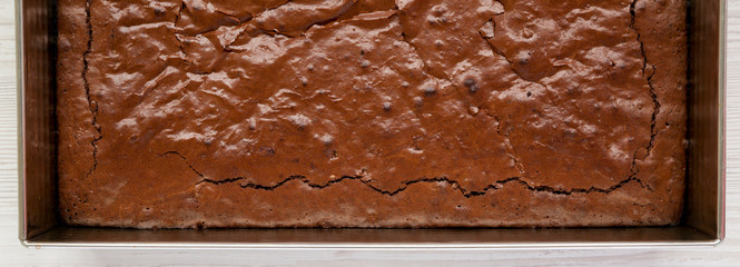 Homemade chocolate brownie on a white wooden surface, top view. Overhead, from above, flat lay....