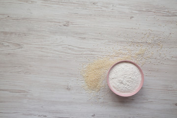 Gluten free rice flour in a pink bowl over white wooden surface, top view. Space for text.