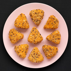 Fried camembert on a pink plate on a black surface, top view. Flat lay, overhead, from above. Close-up.