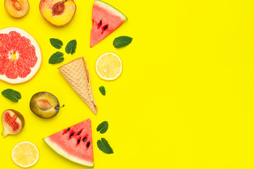 Tropical Summer Fruit Concept. Creative layout made of fresh ripe watermelon, peach, plum, fig, lemon, grapefruit, waffle ice cream cup, mint leaves on yellow background. Flat lay top view copy space