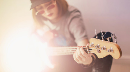 Young beautiful woman musician posing with red bass guitar in a studio	