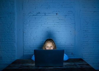 Sad young girl with laptop suffering bullying and harassment online. Cyber bullying victim