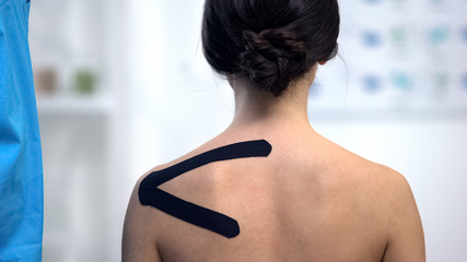 Fototapeta na wymiar Female patient with applied Y-shaped tape on shoulder, alternative medicine