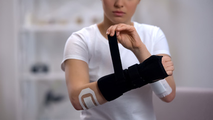 Young sportswoman applying titan wrist brace rehabilitation after trauma, health