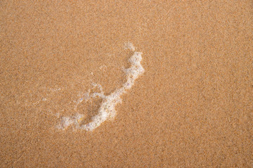 Sand of a beach with foam of the surf