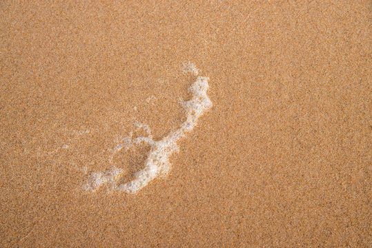 Sand of a beach with foam of the surf