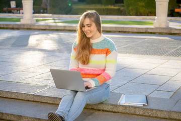 Attractive young woman studying or working with laptop outside in european city