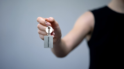 Happiness word on keychain in female hand, independent achievement of success